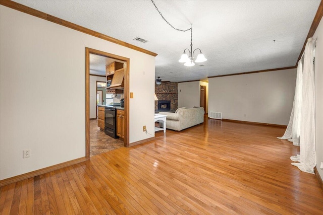 unfurnished living room featuring a textured ceiling, a notable chandelier, a stone fireplace, and wood-type flooring