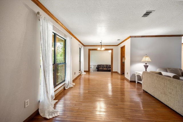 living room with wood-type flooring, a chandelier, crown molding, and a textured ceiling