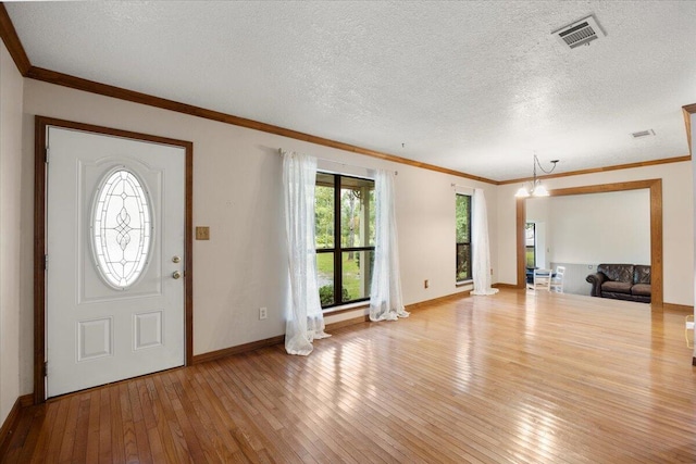 entryway with a textured ceiling, crown molding, and light wood-type flooring