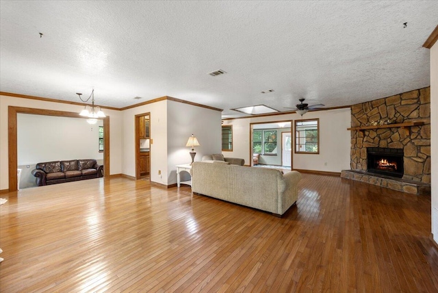 living room featuring a textured ceiling, light hardwood / wood-style flooring, and a stone fireplace