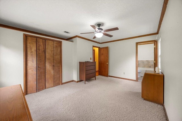 unfurnished bedroom with a textured ceiling, a closet, ensuite bathroom, light colored carpet, and ceiling fan