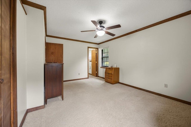 carpeted spare room with a textured ceiling, crown molding, and ceiling fan