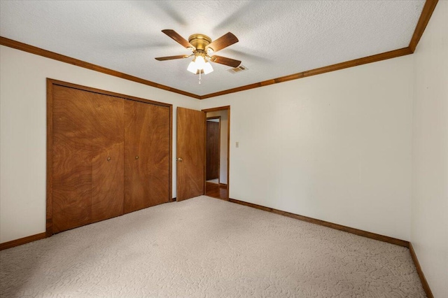 unfurnished bedroom featuring a textured ceiling, a closet, carpet floors, ceiling fan, and ornamental molding