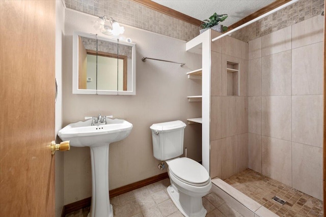 bathroom with tile patterned floors, toilet, sink, tiled shower, and a textured ceiling