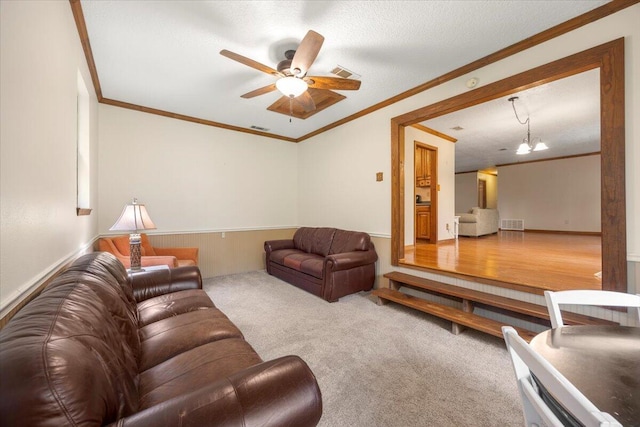 living room with ceiling fan with notable chandelier, a textured ceiling, hardwood / wood-style flooring, and ornamental molding