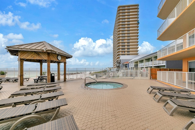 view of swimming pool featuring a water view, a view of the beach, a gazebo, and a hot tub