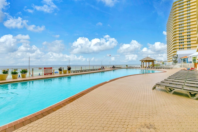 view of pool featuring a water view, a patio area, and a gazebo