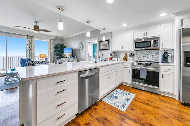 kitchen with hardwood / wood-style flooring, decorative light fixtures, appliances with stainless steel finishes, kitchen peninsula, and ceiling fan