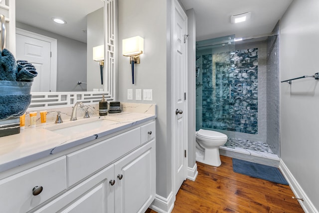 bathroom with vanity, toilet, hardwood / wood-style flooring, and tiled shower