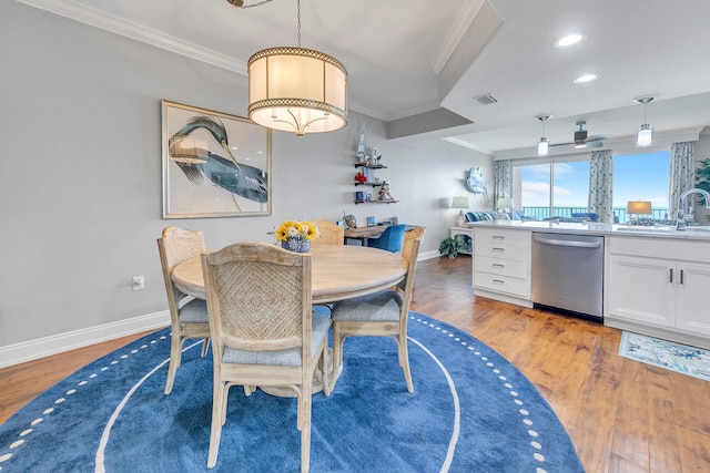 dining area with crown molding, light hardwood / wood-style flooring, and sink