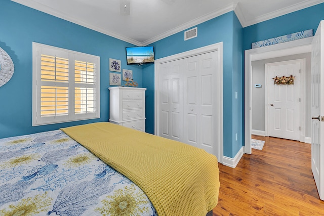 bedroom with crown molding, light hardwood / wood-style flooring, ceiling fan, and a closet