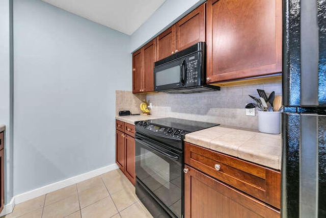 kitchen featuring black appliances, tile counters, light tile patterned floors, baseboards, and backsplash