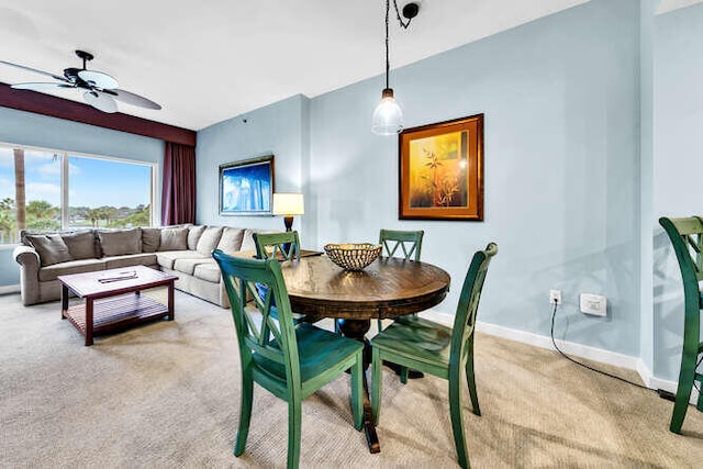 dining room featuring light colored carpet, ceiling fan, and baseboards