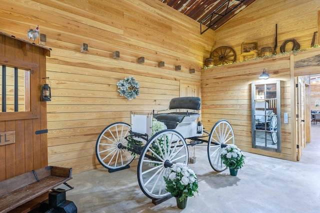 misc room featuring vaulted ceiling, concrete floors, and wooden walls