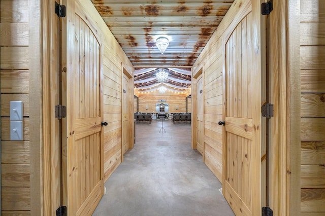 hallway with wood walls, wooden ceiling, and concrete flooring