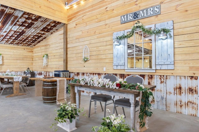 interior space with lofted ceiling, wooden walls, and concrete floors