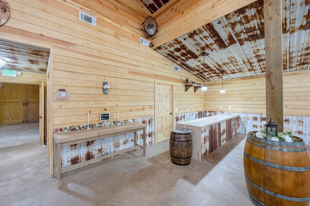 misc room featuring lofted ceiling and wood walls