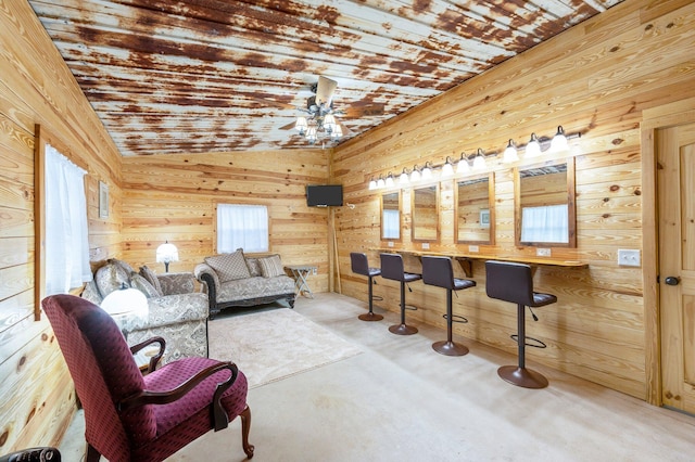 living room with vaulted ceiling, plenty of natural light, ceiling fan, and wooden walls