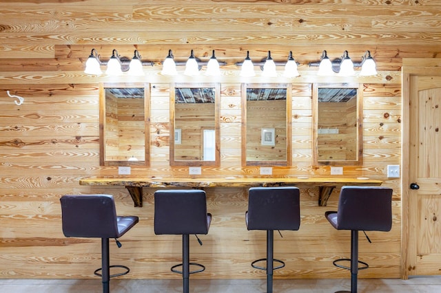 bar with light brown cabinets and wooden walls