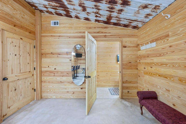 interior space featuring lofted ceiling and wooden walls