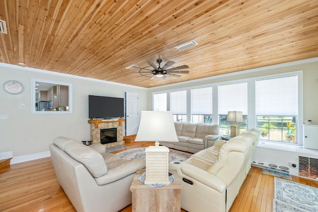 living room with ceiling fan, wood ceiling, light hardwood / wood-style floors, and a stone fireplace