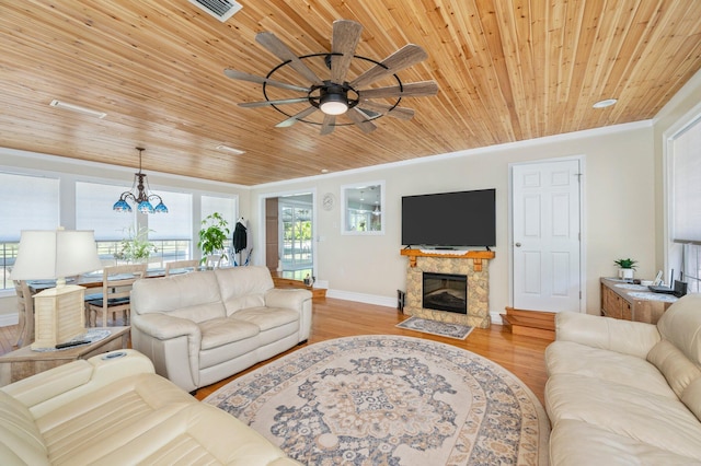 living room with light hardwood / wood-style flooring, wooden ceiling, ceiling fan with notable chandelier, a stone fireplace, and ornamental molding