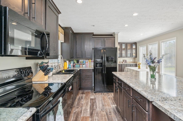 kitchen featuring a textured ceiling, dark hardwood / wood-style flooring, dark brown cabinets, black appliances, and sink