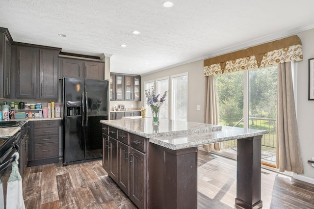 kitchen featuring black appliances, dark hardwood / wood-style floors, dark brown cabinetry, and a kitchen island