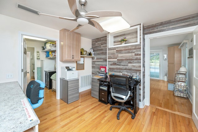 office with light hardwood / wood-style flooring, ceiling fan, and wooden walls