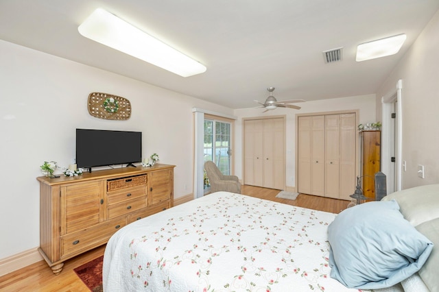 bedroom featuring two closets, ceiling fan, and light hardwood / wood-style floors