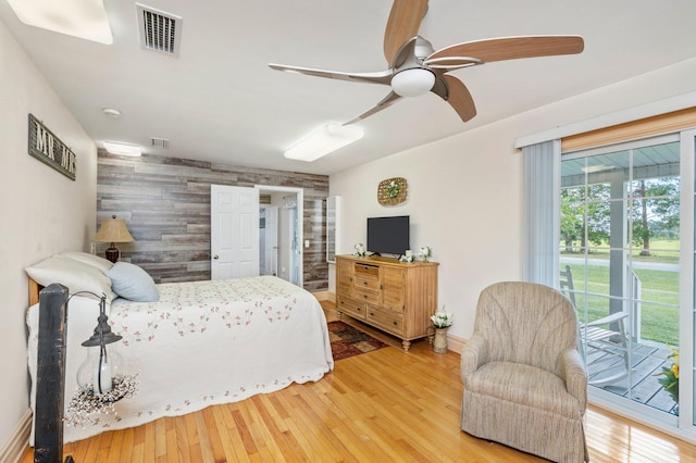 bedroom with wood walls, ceiling fan, hardwood / wood-style flooring, and access to outside