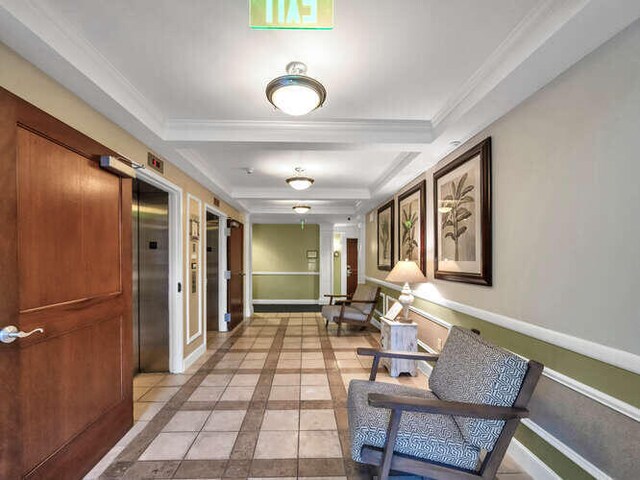 hallway with ornamental molding, elevator, and light tile patterned flooring