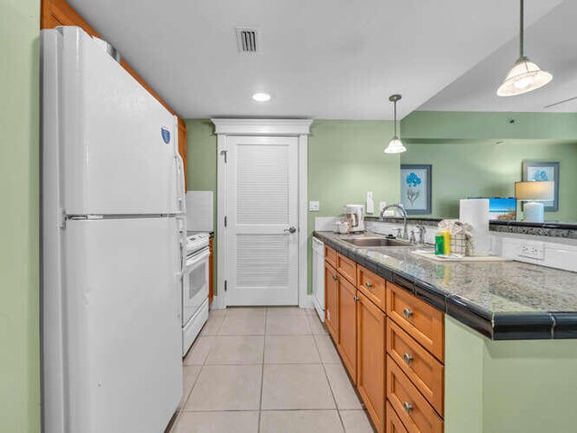 kitchen featuring sink, kitchen peninsula, hanging light fixtures, white appliances, and light tile patterned floors