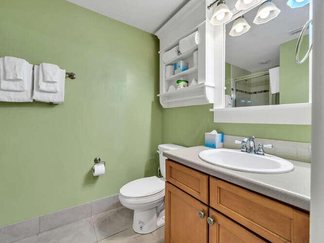 bathroom with tile patterned flooring, vanity, toilet, and a shower with shower door