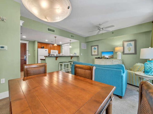 dining room featuring light carpet and ceiling fan