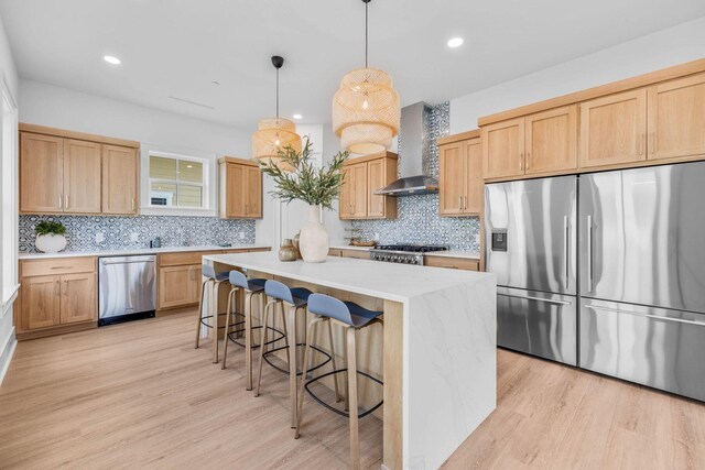 kitchen with light wood-type flooring, tasteful backsplash, hanging light fixtures, a kitchen island, and stainless steel appliances