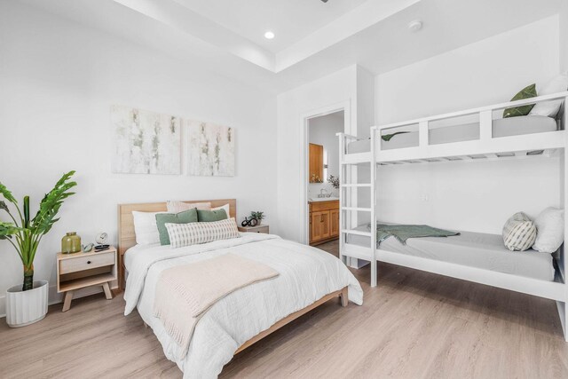 bedroom with sink, connected bathroom, and light hardwood / wood-style floors