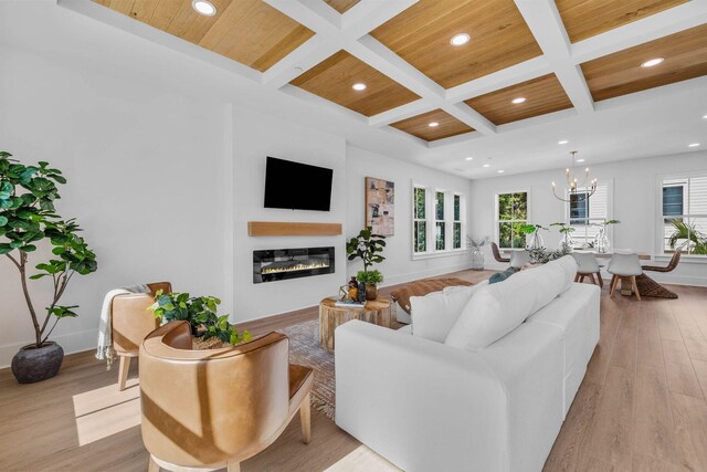 living room featuring light wood-type flooring, coffered ceiling, beam ceiling, and a chandelier