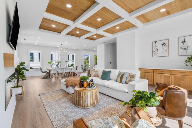 living room with beamed ceiling, wood ceiling, coffered ceiling, a notable chandelier, and light wood-type flooring