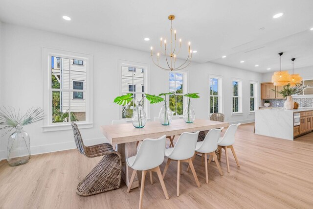 dining area featuring a healthy amount of sunlight, light hardwood / wood-style floors, and a notable chandelier