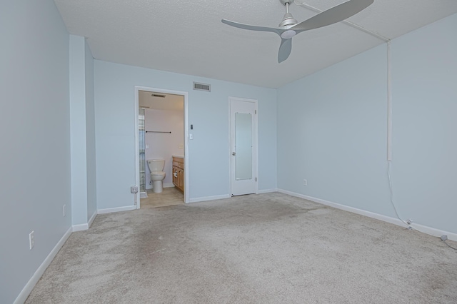 unfurnished bedroom with ceiling fan, light colored carpet, ensuite bath, and a textured ceiling