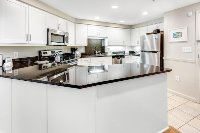 kitchen with stainless steel appliances, white cabinets, kitchen peninsula, and light tile patterned floors