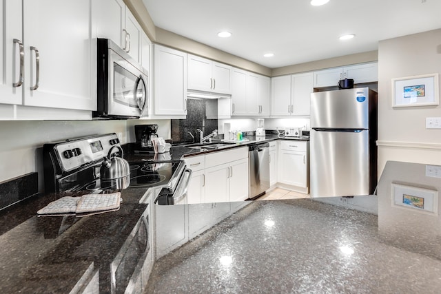 kitchen with dark stone counters, white cabinetry, appliances with stainless steel finishes, and sink