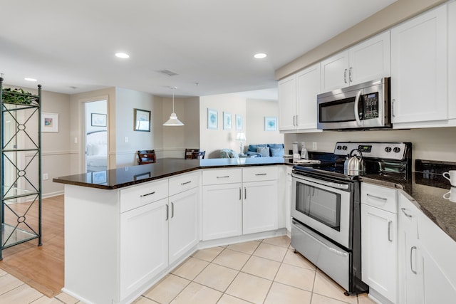 kitchen featuring kitchen peninsula, white cabinetry, appliances with stainless steel finishes, dark stone countertops, and light wood-type flooring