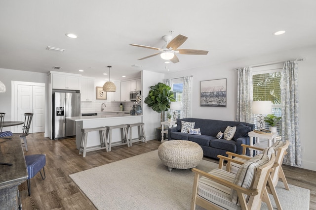 living room featuring ceiling fan, plenty of natural light, and dark hardwood / wood-style flooring