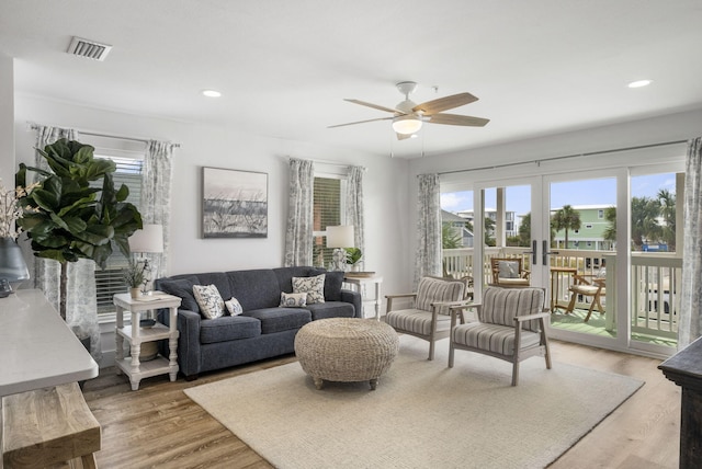 living room with ceiling fan, a fireplace, wood-type flooring, and french doors