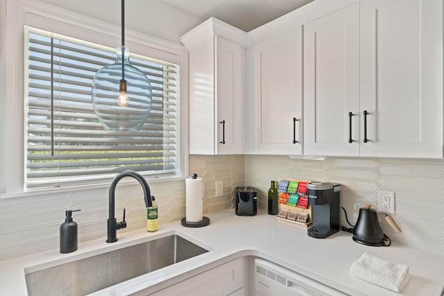 kitchen featuring white cabinets, pendant lighting, sink, and decorative backsplash