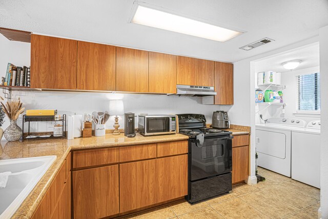 kitchen featuring light tile patterned floors, black range with electric cooktop, separate washer and dryer, and sink