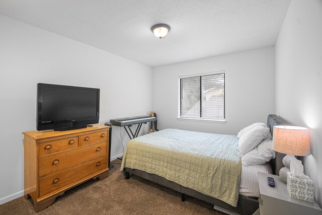 bedroom with dark colored carpet and a textured ceiling