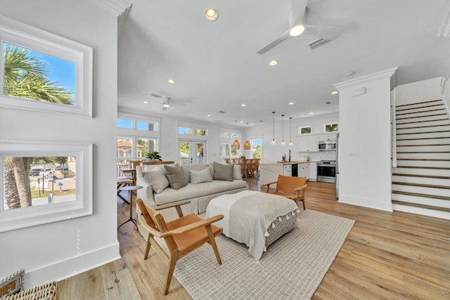 living room with ornamental molding, a healthy amount of sunlight, ceiling fan, and light hardwood / wood-style floors